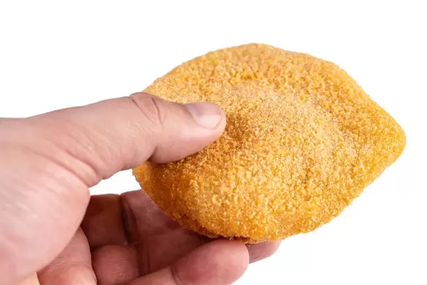 Hand hält Cordon Bleu - paniertes Putenfleisch, gefüllt mit Schinken und Käse, isoliert vor weißem Hintergrund