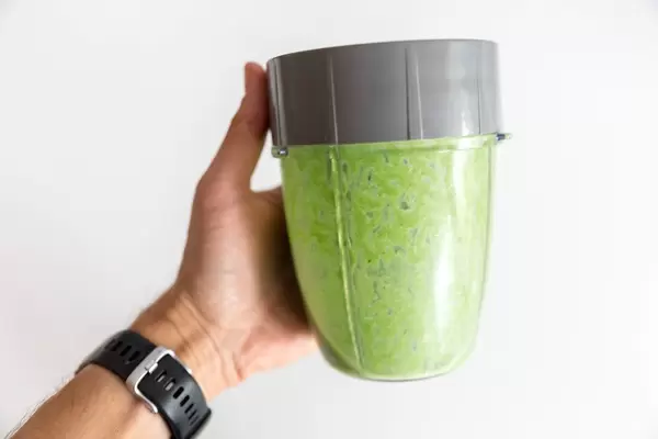 Hand hält das gefüllte Mixer-Gefäß von Mr. Magic vor einer weißen Wand