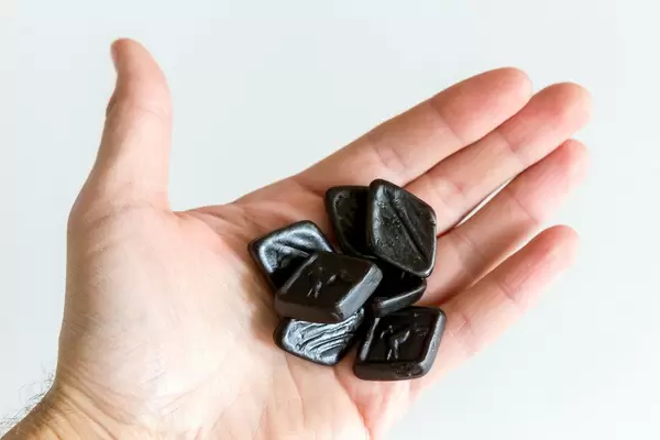 Hand hält die handlichen, viereckigen "Oldtimers van Autodrop" - Lakritz, eine Süßigkeit aus den Niederlanden