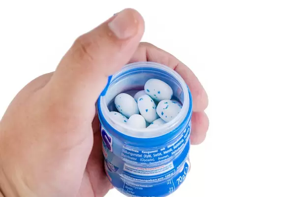 Hand hält die Plastikverpackung der Mentos Kaugummis