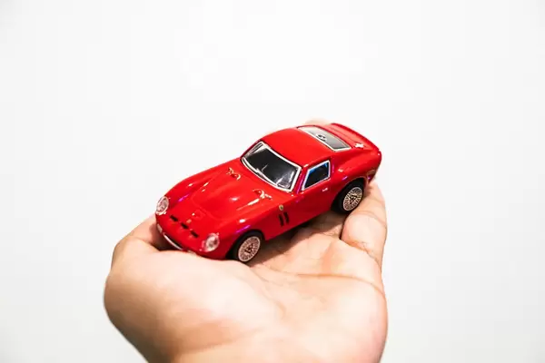 Hand hält ein kleines rotes Auto