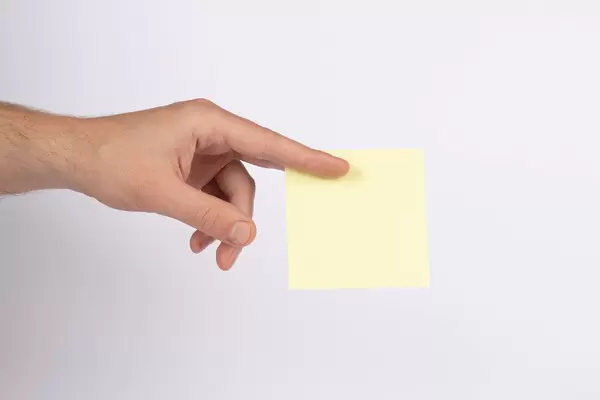 Hand hält ein leeren, gelben Notizzettel