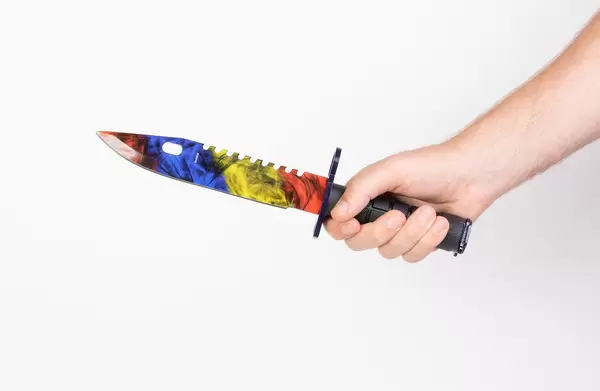 Hand hält ein Rambomesser mit bunter Klinge, vor weißem Hintergrund