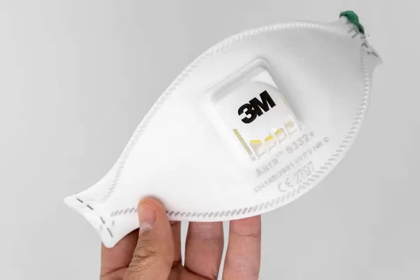 Hand hält eine Aura FFP3 Atemschutzmaske 9332+ von 3M vor weißem Hintergrund