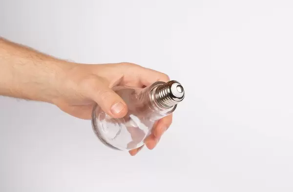 Hand hält eine Glühbirne vor weißem Hintergrund