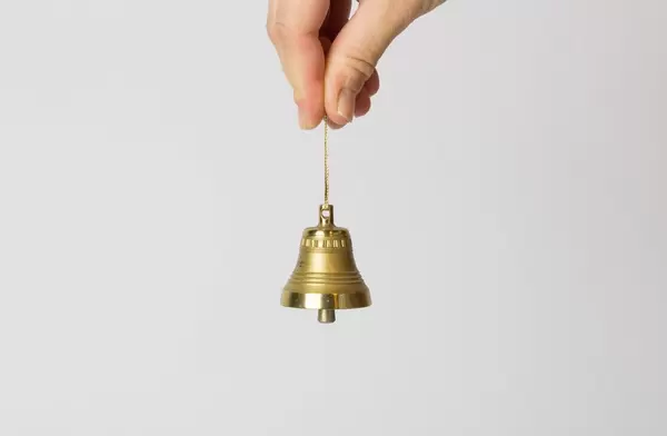 Hand hält eine kleine Glocke