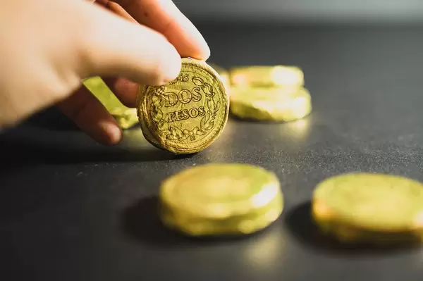 Hand hält eine mexikanische Schokoladenmünze mit dem Aufdruck "Zwei Pesos"