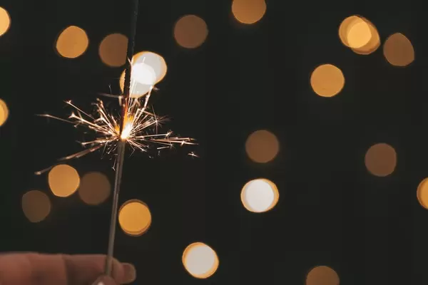 Hand hält eine Wunderkerze vor Bokeh-Hintergrund