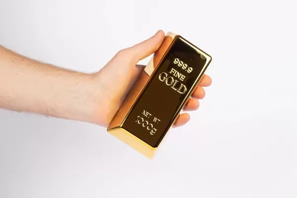 Hand hält einen Goldbarren