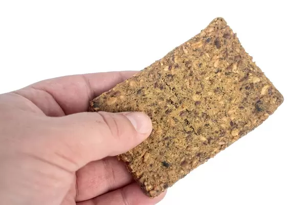 Hand hält einen Proteinriegel mit Kürbiskernen