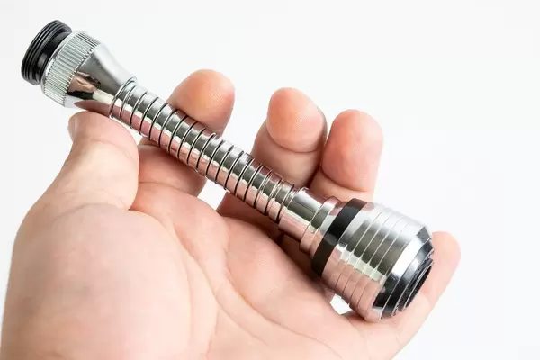 Hand hält einen Wasserhahnadapter für die Küche, mit eingebautem Netz zum Wasser sparen