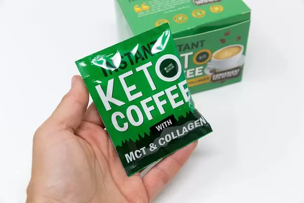 Hand hält grüne Packung von instant Keto Kaffee von ILoveKetoLife mit Kollagen und MCT