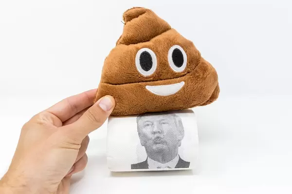 Hand hält Poop Emoji Plüschkissen auf eine Rolle Donald Trump Toilettenpapier