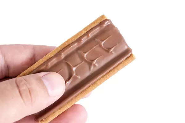 Hand hält Twix Top Schokoladeriegel mit Biskuit vor weißem Hintergrund