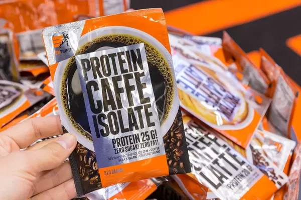 Hand hält Verpackung des isolierten Proteinkaffees von Ex Trifit ohne Zucker und Fett auf der Fibo in Köln