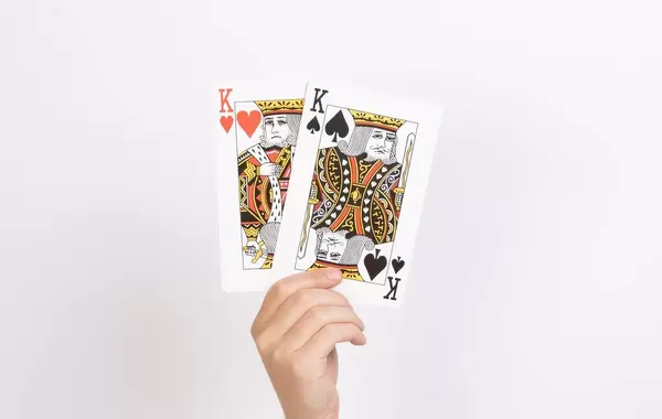Hand hält zwei Könige-Spielkarten vor weißem Hintergrund