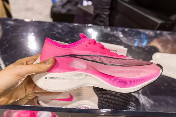Hand hold pink racing shoe for pro athletes: Nike Zoom Vaporfly Next%