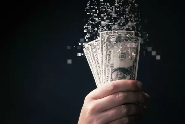 Hand holding 100 dollar bills which are tearing apart