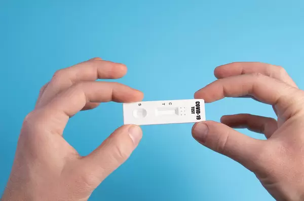Hand holding a covid-19 antigen test on blue background