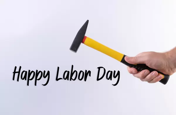 Hand holding a hammer and Happy Labor Day text