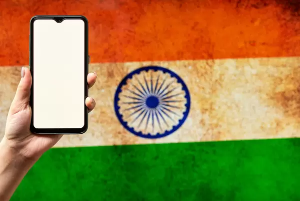 Hand holding a smartphone with a blank screen over the Indian flag
