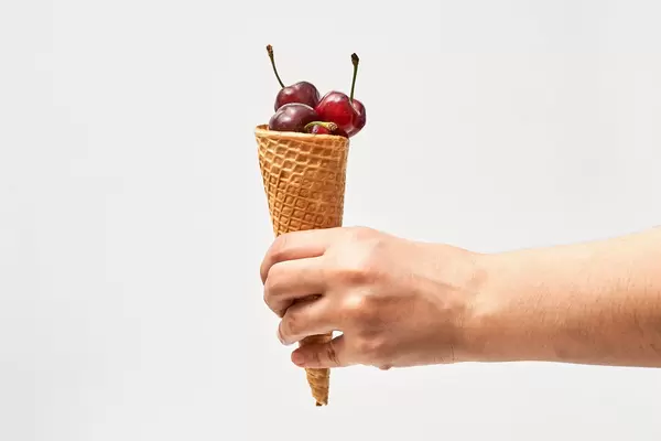 Hand holding a waffle cone full of fresh sweet cherry fruits