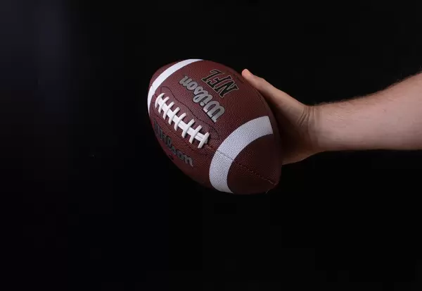 Hand holding american football ball