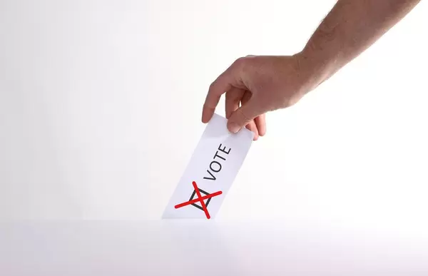 Hand holding ballot paper for election vote concept