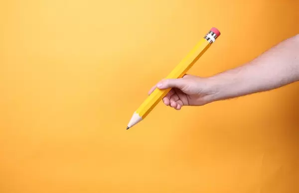 Hand holding big yellow pencil