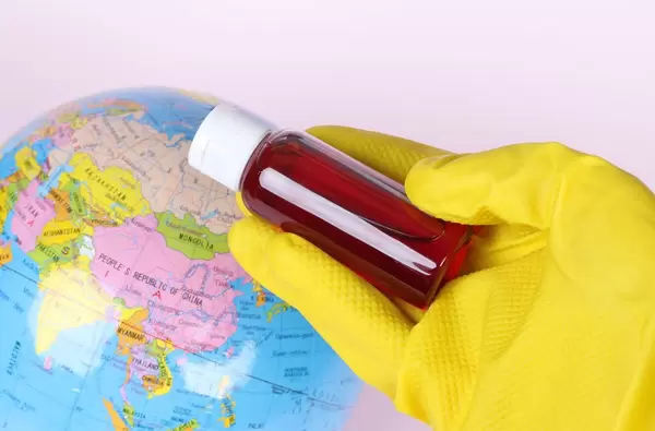 Hand holding blood sample in test tube with globe in the background