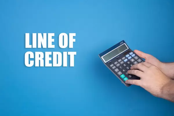 Hand holding calculator and Line of Credit text on blue background