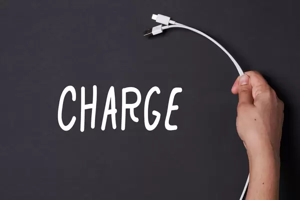 Hand holding charging cable near the Charge text