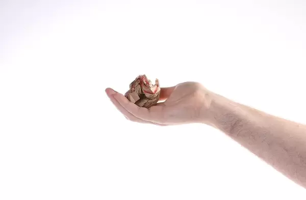 Hand holding crumpled paper on white background