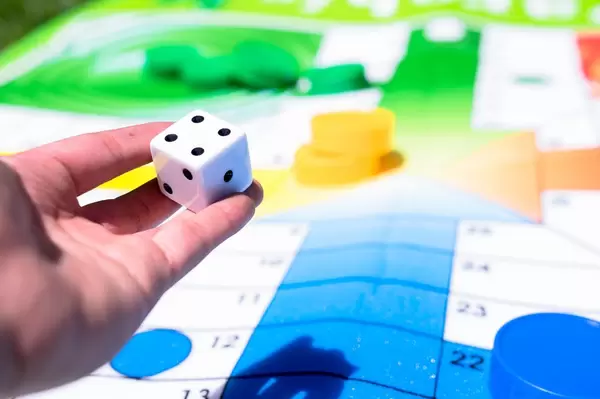 Hand holding dice over giant parchís game mat