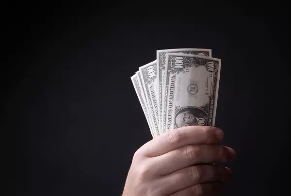 Hand holding dollar banknotes on black background