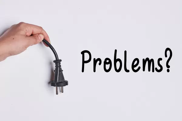 Hand holding electricity cable over white wall with text - Problems