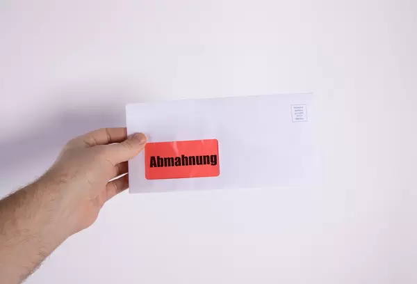 Hand holding envelope with Abmahnung text