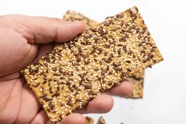 Hand holding Flax and sunflower seeds healthy board