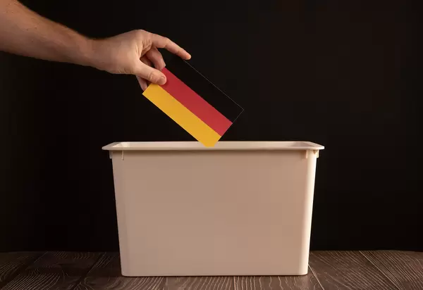 Hand holding German flag over ballout box