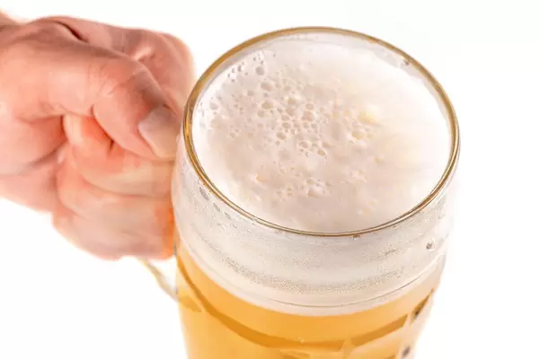 Hand holding glass of beer on a white background, close up