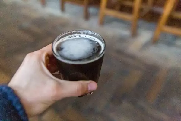 Hand holding glass with Nitro Cold Brew on tap at The Allis in Chicago