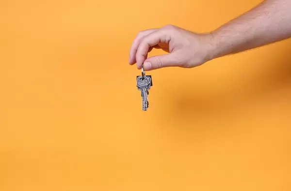 Hand holding keys on orange background