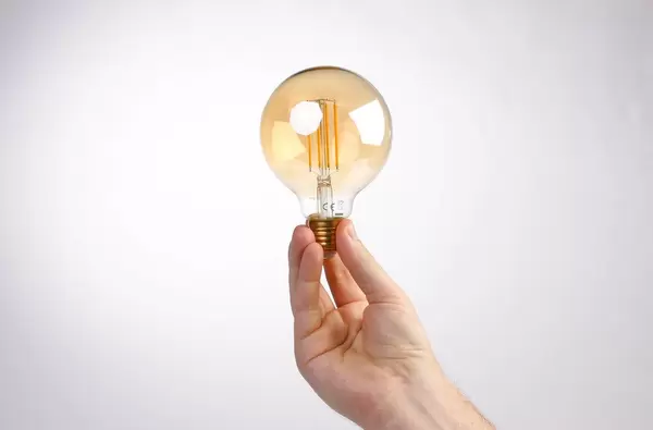 Hand holding lightbulb against white background