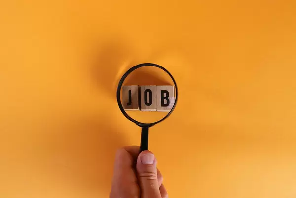 Hand holding magnifying glass over Job text