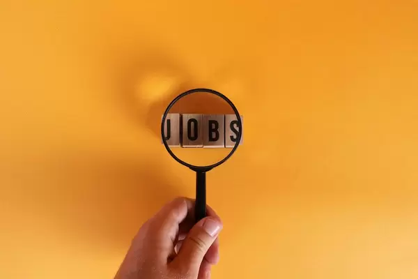 Hand holding magnifying glass over Jobs text