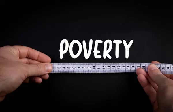 Hand holding measure tape and Poverty text on black background