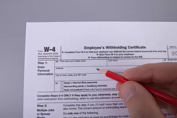 Hand holding pencil and filling out W-4 form