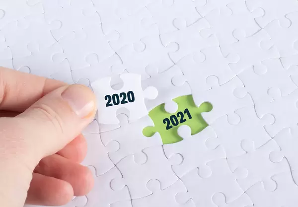 Hand holding piece of jigsaw puzzle with text 2020 & 2021