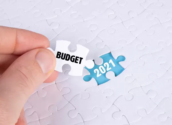 Hand holding piece of jigsaw puzzle with text budget & 2021