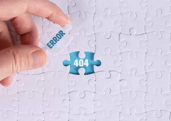 Hand holding piece of jigsaw puzzle with word error & 404
